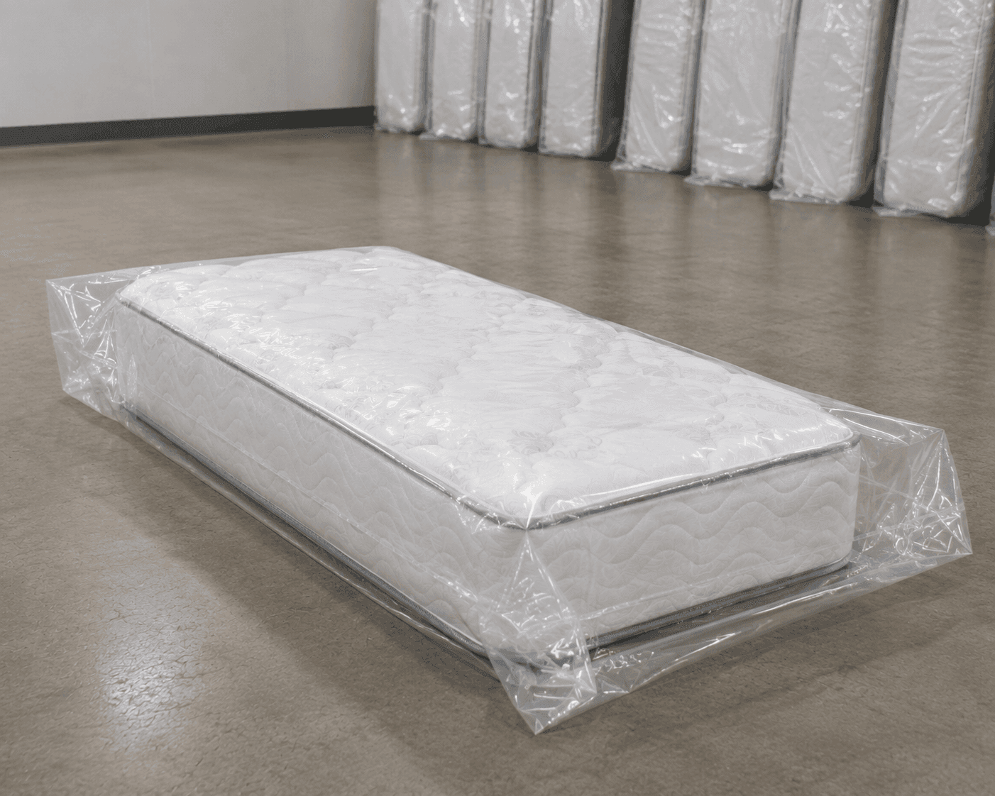 Twin mattress lying flat inside a clear protective mattress bag